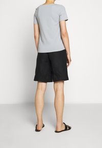 Lys grå kortærmet t-shirt parret med sorte shorts, præsenteret fra ryggen, med en afslappet pasform og minimale designdetaljer.