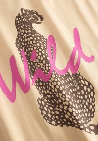 Tissu beige avec une silhouette de léopard en brun foncé parsemée de taches blanches, accompagné du mot "Wild" en rose vif.