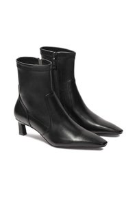Crne kožne gležnjače s izrazito špicastim vrhom, niskom petom i bočnim patentnim zatvaračem. Glatka tekstura i elegantan dizajn s minimalnim detaljima šivanja.