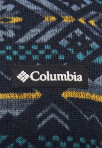 Pletená svetr fabric s geometrickým vzorem v tmavě modré, tyrkysové a žluté barvě. Obsahuje černou etiketu s bílým logem "Columbia".