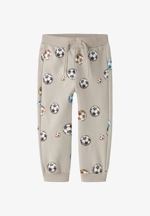 Beige børnebukser med elastisk talje og snøre, med et spredt mønster af brune, blå og sorte fodboldbolde.