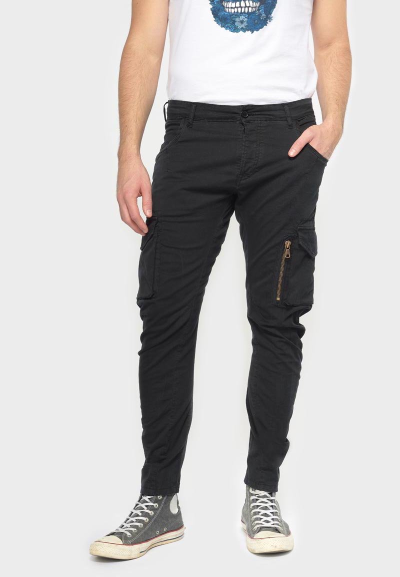 Zwarte cargobroek met ritszakken, gemaakt van katoenen stof. Tapered fit met zijzakken, gecombineerd met grijze hoge sneakers.