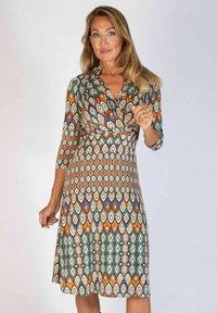 Mehrfarbiges Kleid mit Wickeldesign, das ein geometrisches Muster aus Rauten in Erdtönen und Türkis zeigt. Strukturierter Stoff, knielang.