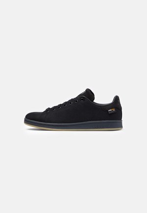 Niedriger schwarzer Sneaker mit schwarzen Schnürsenkeln, strukturiertem Stoffoberteil, Gummisohle und kleinem Cordura-Stoffetikett an der Seite.