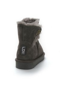 Stivale alla caviglia in suede grigio con rivestimento in pelliccia sintetica, punta tonda, suola piatta in gomma e dettagli in metallo dorato con logo sul retro.