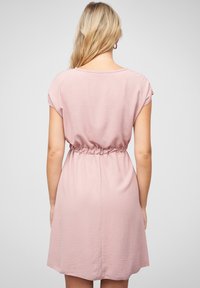 Short pink dress with a relaxed fit, featuring short sleeves, an elastic waistband, and a smooth textured fabric. Back view shown.