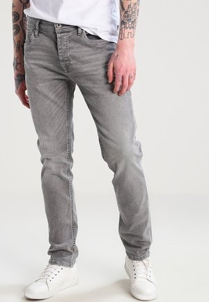 Grå denimjeans med en figurnära design, ljus tvätt, femficksstil och subtila sömnadsdetaljer, parat med vita sneakers.