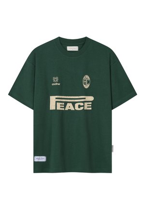 Dunkelgrünes T-Shirt mit beigem Text "PEACE" und kleinen Logos mit den Aufschriften "another" und "ACL 2023" auf der Vorderseite, kurze Ärmel, Rundhalsausschnitt.