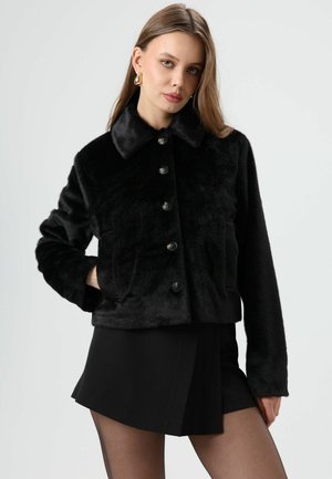 Veste en fausse fourrure noire avec un col à revers, une fermeture à boutons sur le devant et des poches latérales. Texture lisse et coupe courte.