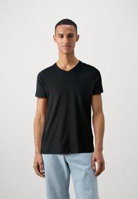 Czarny t-shirt z krótkim rękawem i dekoltem w kształcie litery V, wykonany z miękkiej bawełny, o dopasowanym kroju i gładkiej fakturze, w połączeniu z jasnoniebieskimi dżinsami.