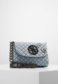 Borsa a spalla in denim trapuntato blu chiaro con tracolla a catena nera, cintura in pelle con fibbia nera, emblema del logo e due strass decorativi sulla patta.