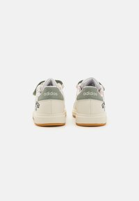 Baltās un zaļās Adidas sporta apavus ar teksturētu aizmuguri, logotipa akcentiem un gaismas krāsas zoli ar rakstainu iekšpusi.