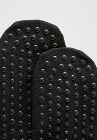 Calze antiscivolo nere con punti di gomma testurizzati per una maggiore aderenza. Tessuto a maglia con una finitura liscia e forma della punta arrotondata.