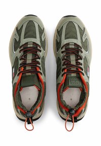 Green and beige sneakers with mesh and leather materials. Features include black outsole, orange accents, and elastic laces with toggle.