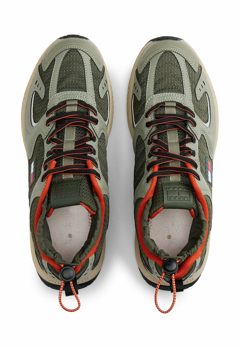 Green and beige sneakers with mesh and leather materials. Features include black outsole, orange accents, and elastic laces with toggle.