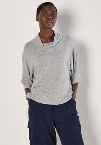 Helles graues, strukturiertes Sweater mit Kragen und 3/4-Ärmeln, kombiniert mit navy gestreiften Cargo-Hosen mit Seitentaschen.