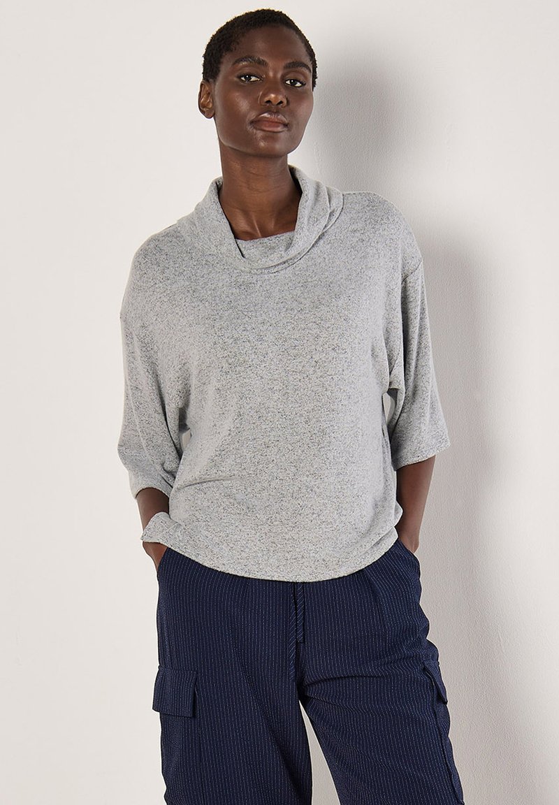 Helles graues, strukturiertes Sweater mit Kragen und 3/4-Ärmeln, kombiniert mit navy gestreiften Cargo-Hosen mit Seitentaschen.