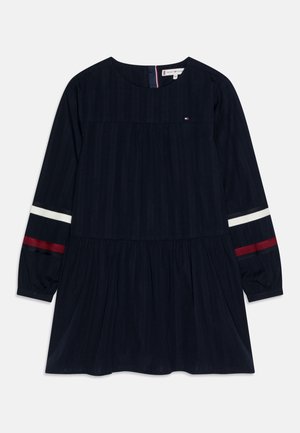 Marineblaues Kleid mit langenärmeln, plissiertem Rock und gestreiften Akzenten in Weiß und Rot. Aus Baumwollmaterial mit rundem Ausschnitt und Rückenverschluss.