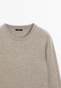 Maglione lavorato a maglia grigio chiaro con scollo rotondo, texture morbida e motivo sottile. Etichetta all'interno con il nome del marchio.