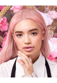 Portrait of a person with long, straight pastel pink hair, wearing a white shirt with black accents, showcasing glossy lips and a silver ring.