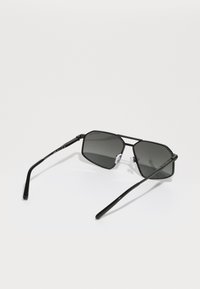 Occhiali da sole in stile black metal con lenti esagonali, tonalità grigia e stanghette sottili. Presentano cuscinetti nasali trasparenti e dettagli in acetato sulla montatura.