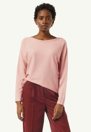 Pink long-sleeve top in soft, textured fabric with a wide neckline, paired with high-waisted burgundy trousers. Minimalist design.