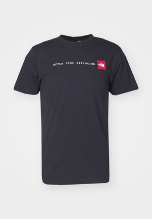 T-shirt nera in cotone con collo a giro, caratterizzata dalla frase "NEVER STOP EXPLORING" in bianco e un piccolo logo rosso sul lato sinistro del petto.