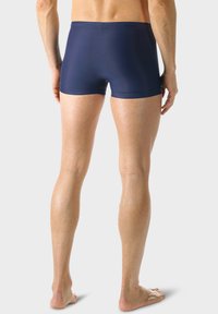Námořnické plavkové šortky z hladkého pružného materiálu, přiléhavého střihu a délky do poloviny stehna. Obsahují bezšvový pás pro pohodlí.