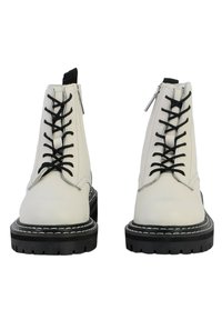 Botas de piel blancas hasta el tobillo con cordones negros, cremalleras laterales y una suela negra gruesa con costuras blancas y un dibujo texturizado.