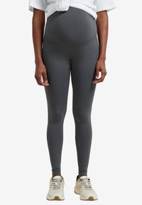 Gray leggings with a smooth, stretchy fabric, high waistband for support, paired with a loose white shirt and neutral sneakers.