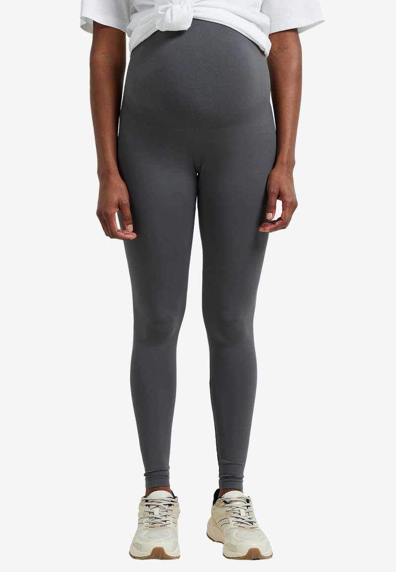 Gray leggings with a smooth, stretchy fabric, high waistband for support, paired with a loose white shirt and neutral sneakers.