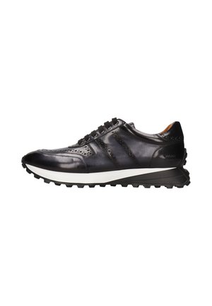Zapatilla deportiva de cuero negro con acentos perforados, suela texturizada y entresuela blanca. Presenta cordones negros y un diseño de punta redondeada.