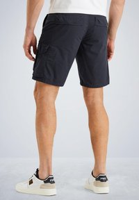 Mornarska cargo shorts s dva bočna džepa, glatkom teksturom tkanine i ravnim krojem, u kombinaciji s bijelim tenisicama i ležernom majicom.