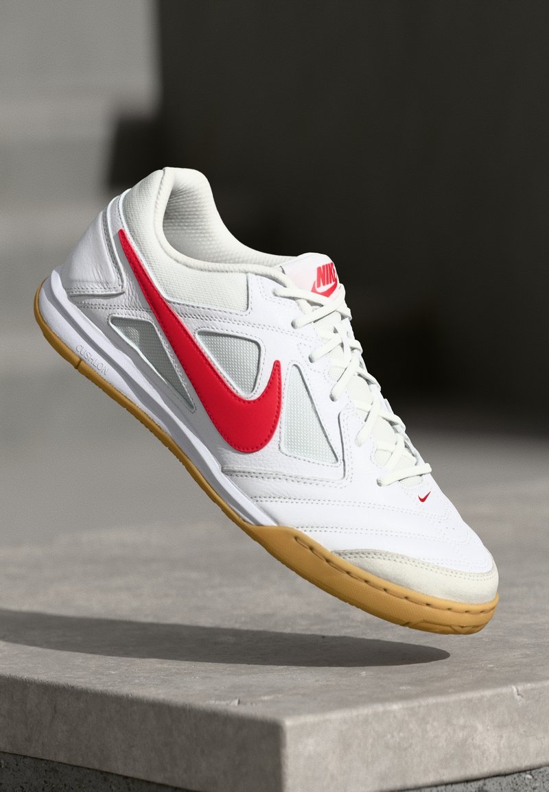 Valge sportlik king, millel on punased aksendid ja Nike'i logo. Omab hingavat võrkkonstruktsiooni, kummist põhja ja pehmet siseruumi.