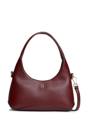 Sac à main en cuir rouge foncé avec une poignée supérieure incurvée, des ferrures dorées et une petite boucle logo dorée au centre avant.