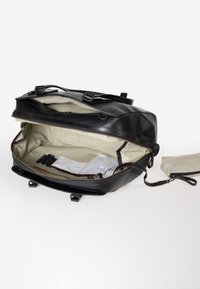 Schwarzer Leder-Rucksack mit einem Reißverschlussöffnugn, beigem Innenraum und gestreiftem Futter. Enthält eine abnehmbare Tasche und verstellbare Träger.