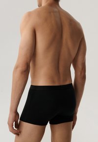 Bokserki z czarnej bawełny, o dopasowanym kroju z elastycznym pasem i minimalną ilością szwów dla komfortu. Widok tylny modela.