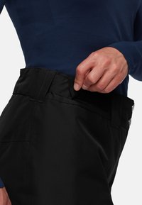 Pantalons noirs avec une fermeture velcro à la taille. Tissu lisse avec une coupe ajustée. Comprend des boutons en métal et une chemise à manches longues bleue.