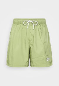 Světlé zelené plavky vyrobené z hladkého, lehkého materiálu. Mají elastický pas se šňůrkou a bílým logem Nike na přední straně.