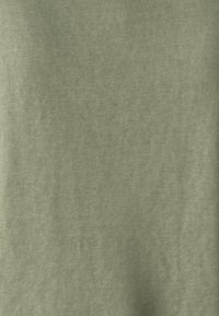 Tissu vert olive clair avec une texture douce et lisse. Le matériau semble léger, affichant un léger éclat et un motif de tissage subtil.