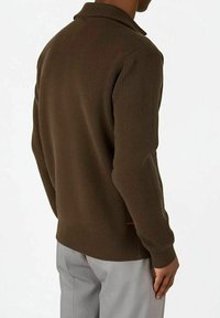 Brun ribbstrikket genser med krage, tettsittende design og teksturert stoff. Har en rød detalj nær den nedre kanten.