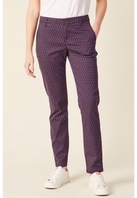 Patterned trousers featuring a geometric design in red and blue on a dark background, with a smooth texture and side pockets.