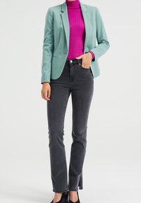 Miętowo zielona marynarka, prążkowany magentowy golf, czarne jeansy z wysokim stanem oraz czarne szpilki. Gładka tkanina, strukturalny design i dopasowana sylwetka.