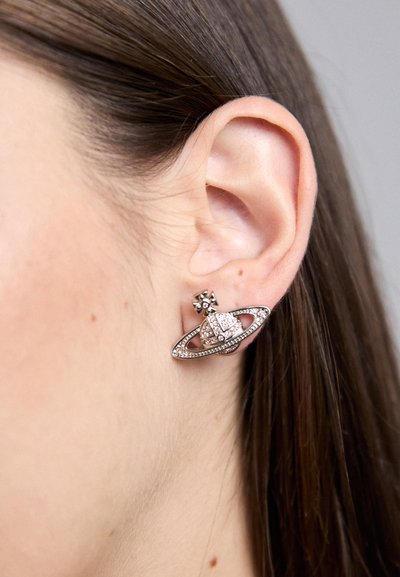 Pendientes en tono plateado con forma de planeta con anillo, adornados con rhinestones rosas y transparentes, y un stud cuadrado en la parte superior.