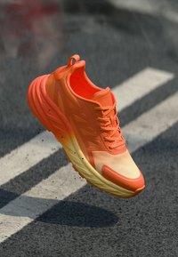 Sapatilha desportiva laranja brilhante com parte superior em malha texturizada, design leve, sola acolchoada e um degradê de laranja para amarelo.
