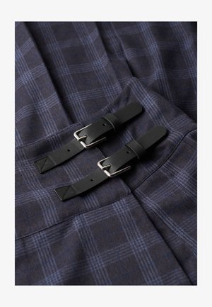 Tela de cuadros náuticos con líneas azul claro, que presenta dos correas negras de cuero con hebillas plateadas y detalles de costura en contraste.