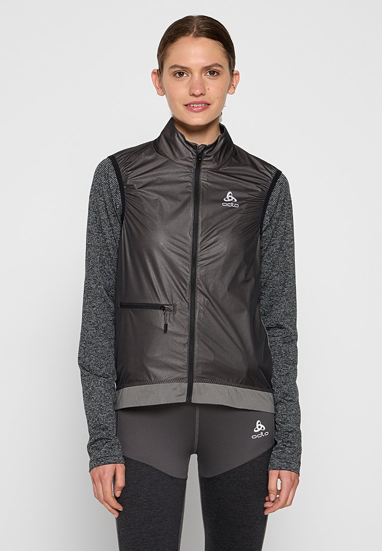 Schwarze ärmellose Weste mit grauen texturierten langen Ärmeln, Reißverschluss, reflektierendem Logo und einer Reißverschlusstasche auf der Vorderseite.