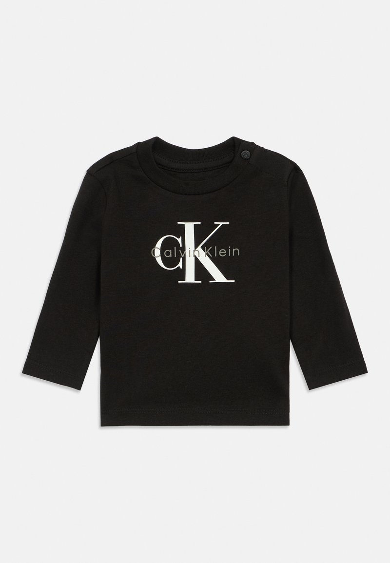 Čierna detská košeľa s dlhým rukávom značky Calvin Klein s bielym a šedým logom "cK" na prednej strane, s okrúhlym výstrihom a gombíkom na ramene.