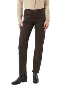 Bruine denimbroek met een rechte pasvorm, voorzien van voor- en achterzakken en een sluiting met zilverkleurige knopen; gecombineerd met zwarte enkellaarzen.