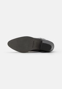 Suela de un zapato negro de piel con punta afilada que muestra la marca Zadig & Voltaire, talla 38, y "Hecho en España" estampado en la parte inferior.